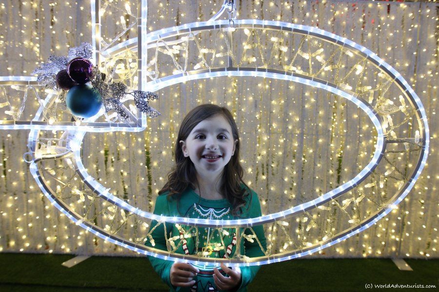 Girl smiling in a frame lit up by Christmas lights