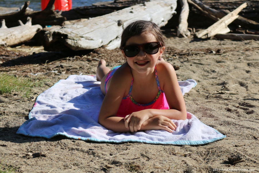 Young girl sun bathing at Birkenhead Lake in Pemberton, BC